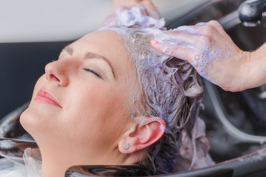 Hairdresser Making Hair Color For Female Client. Caucasian Woman Getting New Hair Color.