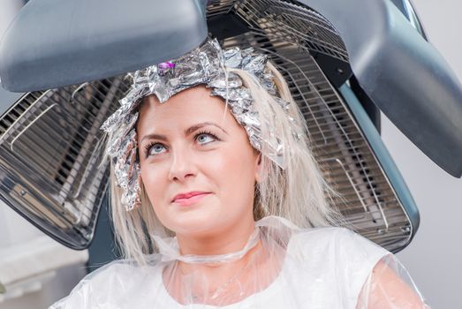 Beauty Salon. Caucasian Woman Under Hair Dryer Awaiting Next Step of Hair Styling.