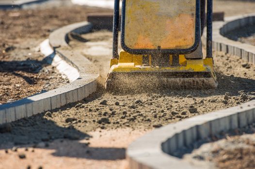 Plate Compactor in Action. Compacting Soil For a Brick Pavement. 