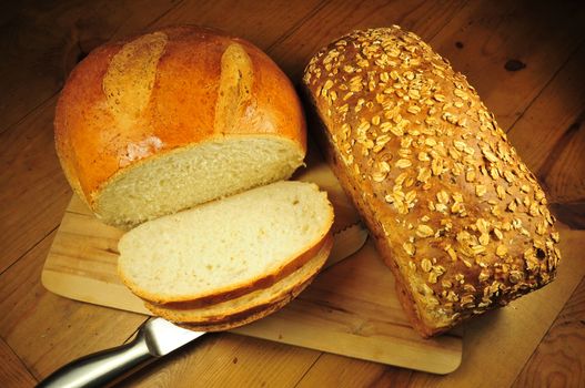 Two Different Fresh Breads. One Bread Sliced. Wood Table.