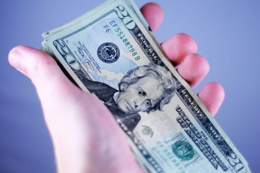 Twenty US Dollars Bills in Hand. Light Blue Background