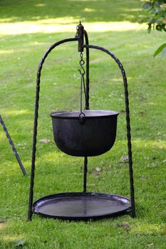 Witches black kettle on forged stand on green grass