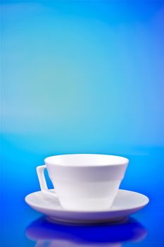 Whiter Small Cup on Blue Background. Vertical Studio Photo.