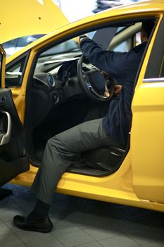 Car Salesman Showing Vehicle Interior. Small Yellow City Car. Dealership.