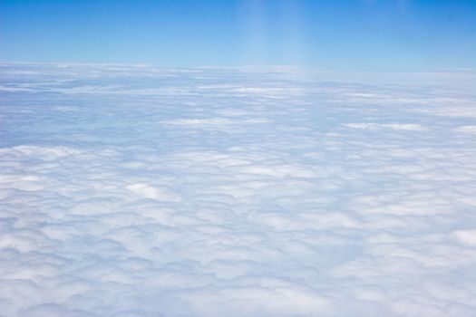 White clouds taken form above while flying in a plane.