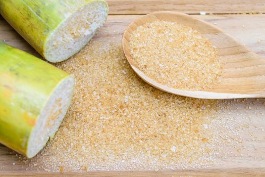 brown sugar and sugarcane on wooden table