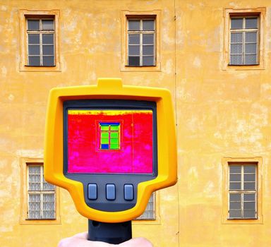 An infrared thermal imager showing building facade and window heat loss.