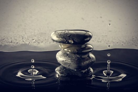 Zen stones in the water with splashing drops. Horizontal image.