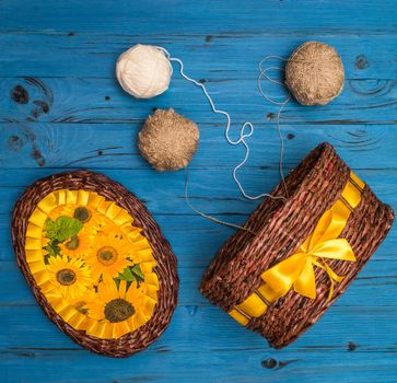 From above white and grey balls of yarn and a wicker basket on blue wooden board in Ukraine