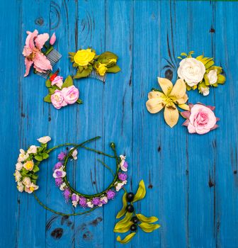 From above different colored artificial flowers and wreaths on a blue wooden board in Ukraine