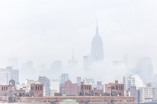 New York City, United States of America - March 24: Misty Manhattan Dimond Reef skyline with Empire State Building and skyscrapers seen from Brooklyn Bridge on March 24, 2015.