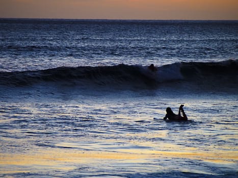 Silhouette of a lone surfer at sunset in Hawaii.