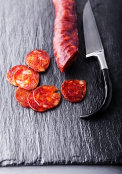 Spanish chorizo with a knife on a stone plate