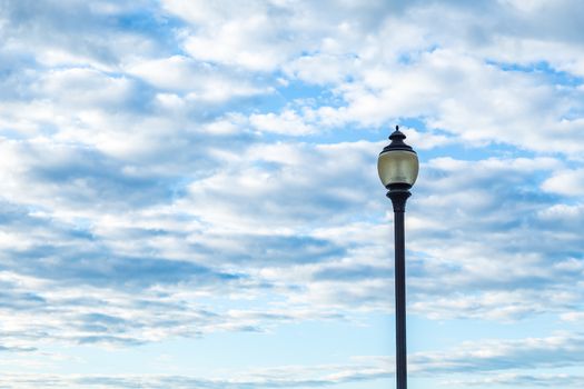 A lamppost in front of a morning sky filled with clouds.