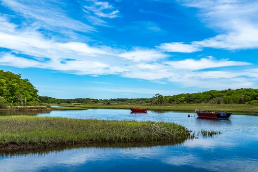 Two boats lay at anchor on the Herring River at Harwich, Massachusetts on Cape Cod.