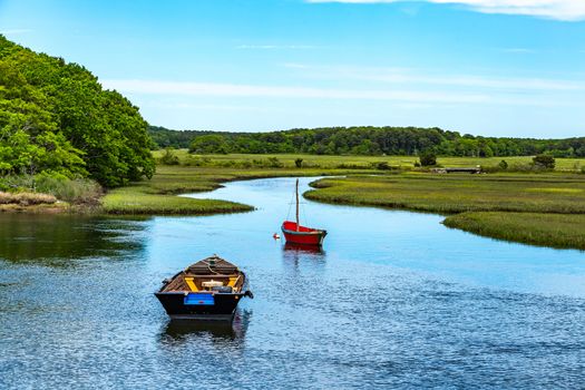 Two boats lay at anchor on the Herring River at Harwich, Massachusetts on Cape Cod.