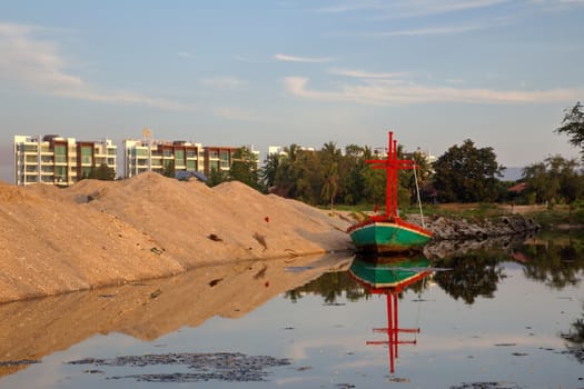 Reflection of Lonely Fisherman boat in dirty water