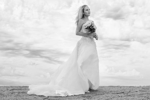 Beautiful bride at the beach with a flower bouquet.