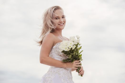 Beautiful bride at the beach with a flower bouquet.