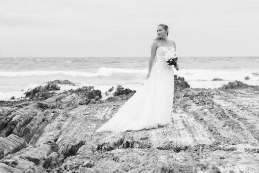 Beautiful bride at the beach with a flower bouquet.