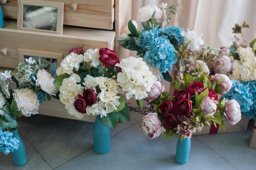 Decor of bouquets of flowers in the studio for photos in rustic style.