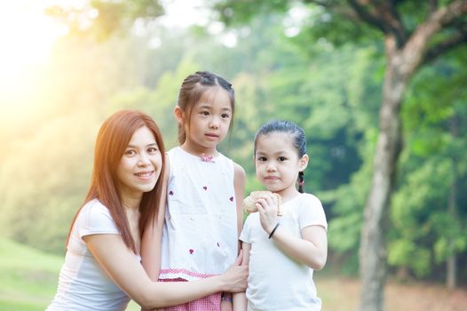 Mother and daughters enjoying in the park, Asian family outdoor lifestyle, morning with sun flare.