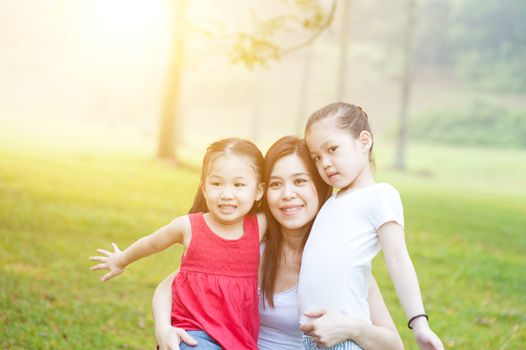 Mother and daughter hugging in love playing in the park. Family outdoor fun, morning with sun flare.