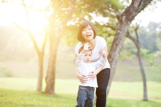 Mother and son are hugging and having fun outdoor in nature. Family outdoor fun, morning with sun flare.