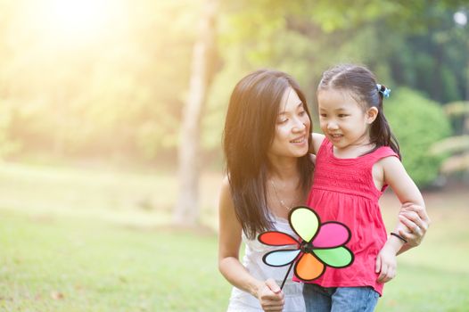 Asian mother and daughter are hugging and having fun outdoor in nature. Family outdoor fun, morning with sun flare.