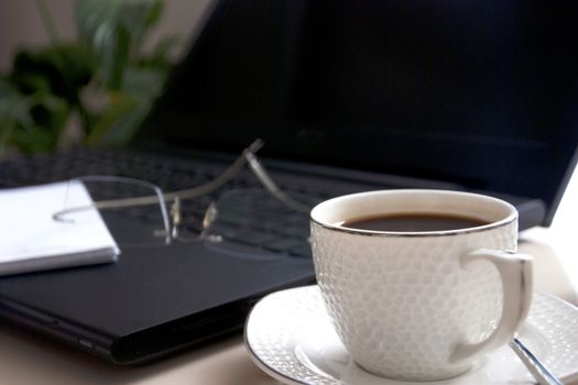 Work desk with laptop computer and hot coffee cup with defocused background.