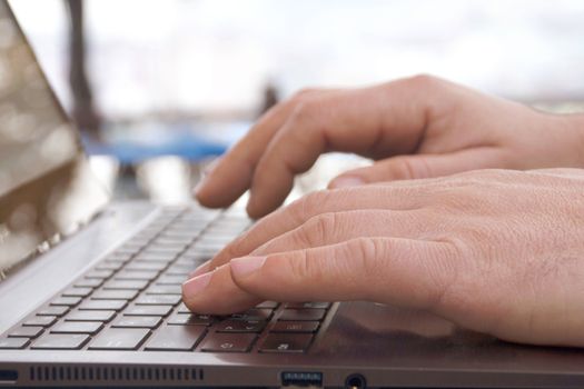 Close-up view of the hands on the keyboard while working with a businessman laptop.