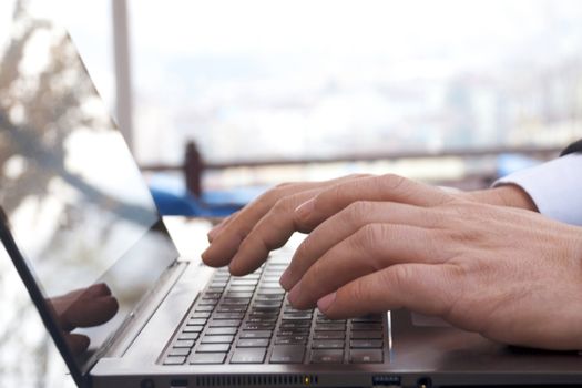 Close-up view of the hands on the keyboard while working with a businessman laptop.