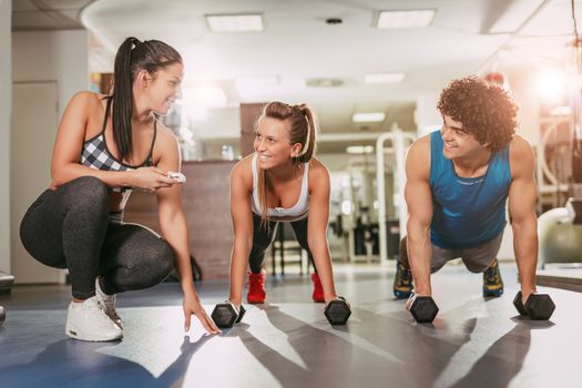 Beautiful happiness couple exercising at the gym with a female personal trainer.