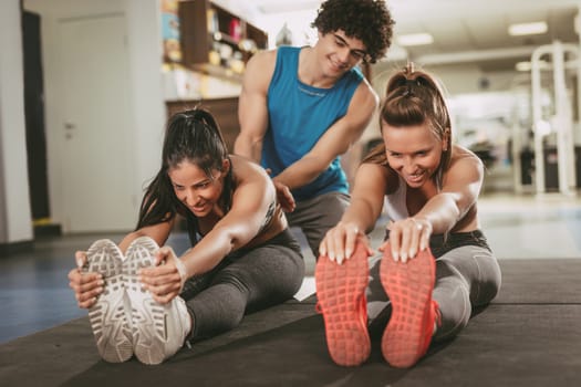 Beautiful smiling girlfriend exercising at the gym with a personal trainer.