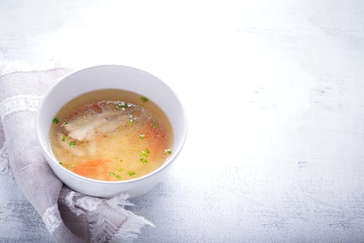 Homemade chicken soup with a spoon on a white napkin