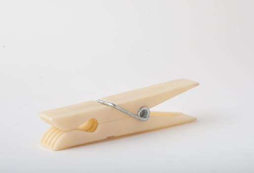 Plastic clothes pin closeup, lying down on side with isolated white background.