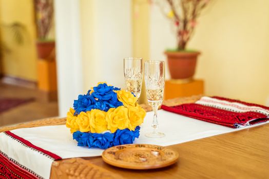 bouquet, rings and glasses of champagne on the embroidered towel on the table in the registry office during the ceremony in Lviv, Ukraine