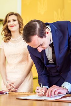 Gorgeous bride and groom signing wedding certificate at the registry office in Lviv, Ukraine
