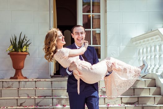 Groom holding bride in his arms after the ceremony at the registry office in Lviv, Ukraine