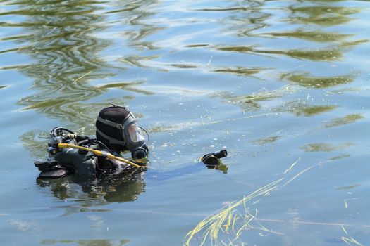 Diver in equipment, with underwater camera performs a search