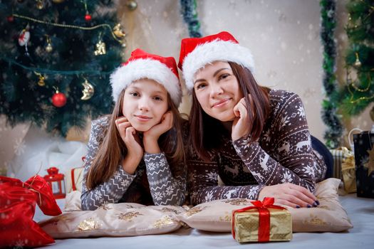 Mother and daughter lying under Christmas tree with gifts
