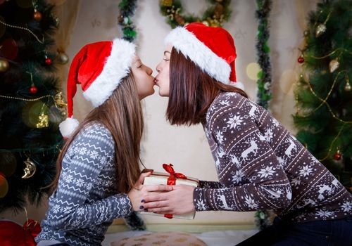 Mother and daughter kissing and holding Christmas gift