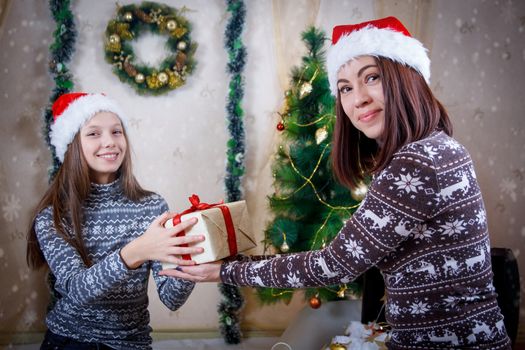 Mother handing Christmas gift to daughter