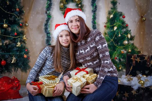Mother and daughter in caps with lot of Christmas gifts