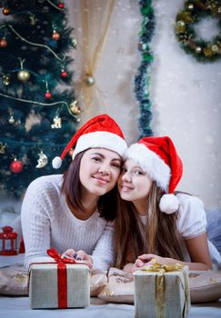 Mother and daughter in Christmas caps lying together