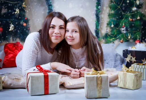 Mother and daughter lying under Christmas tree