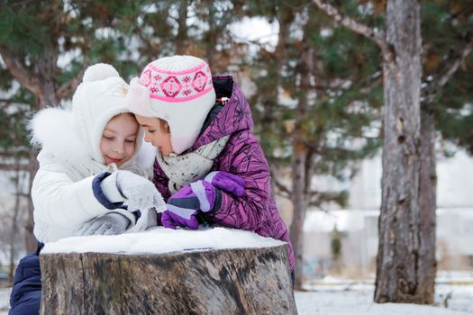 Two cute girls talking among winter park