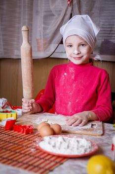 Girl making dough with rolling pin inkitchen