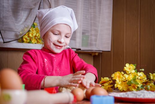 Cute girl in apron rolling dough prepareing cookies