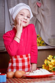 Cute girl playing with dough in kitchen 